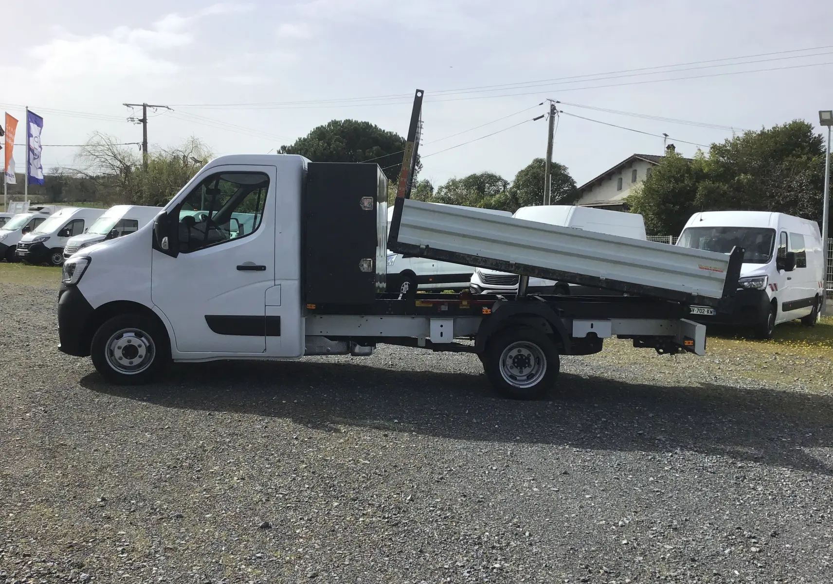 Renault Master Châssis cabine blanc vu de profil côté gauche, avec benne relevée et coffre noir arrière.