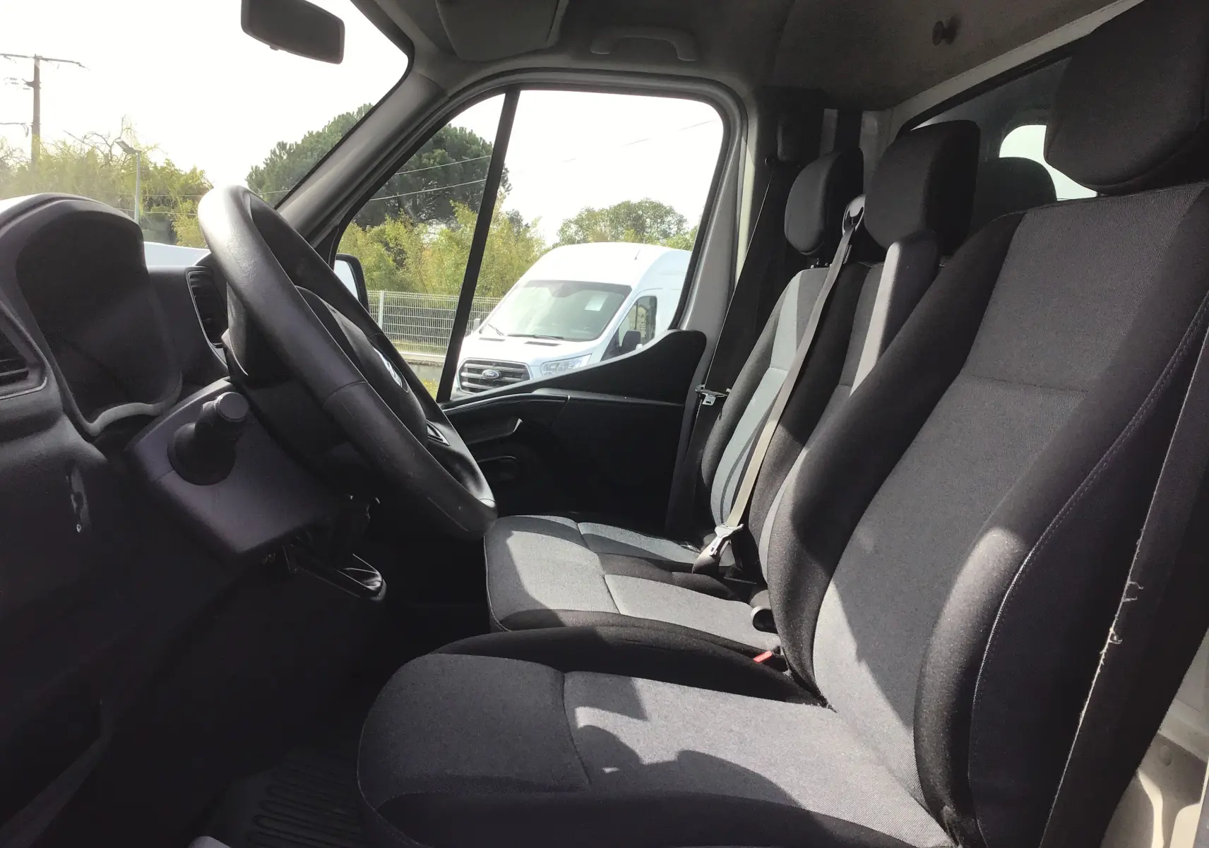 Vue intérieure côté conducteur du Renault Master Châssis Cabine blanc, montrant les sièges avant et le volant.