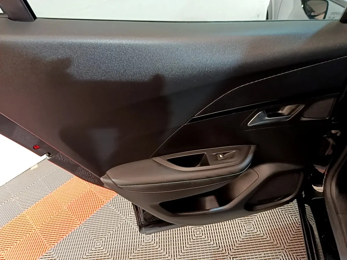 Vue intérieure du panneau de porte avant droit noir du Peugeot 2008 avec commandes de vitre et finition sobre.