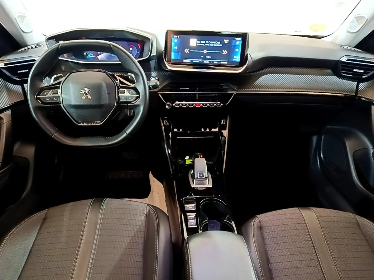 Vue intérieure frontale du tableau de bord du Peugeot 2008 noir, avec écran tactile central et volant multifonctions en cuir.