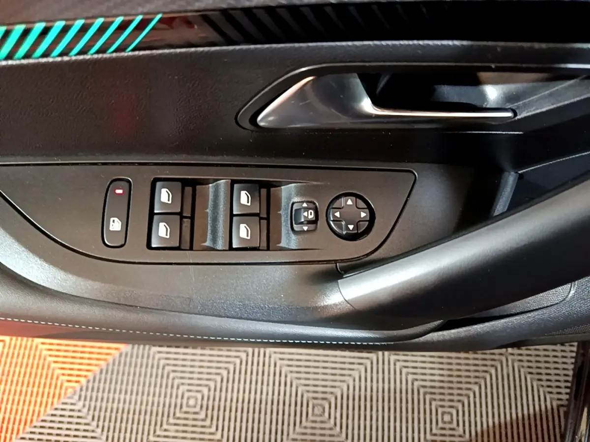 Gros plan sur la commande des vitres et rétroviseurs côté conducteur d’une Peugeot 2008 noire, intérieur noir.
