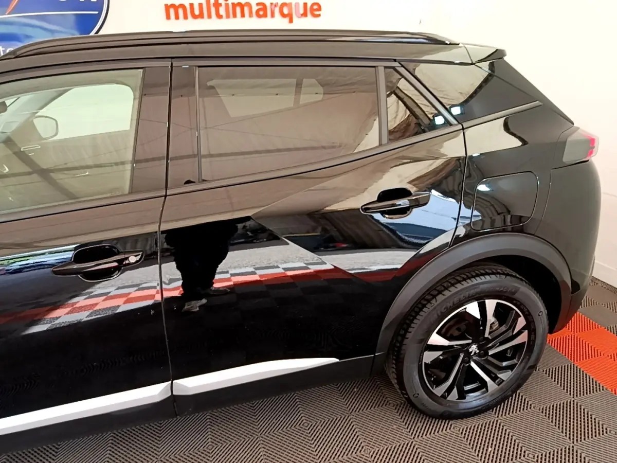 Profil droit noir brillant du Peugeot 2008 2021 avec jantes noires et détails de carrosserie modernes.