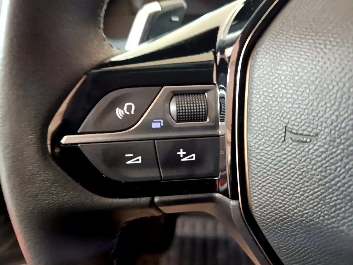 Gros plan sur les commandes gauche du volant cuir noir du Peugeot 2008 2021 version BlueHDi 130 Allure Business.