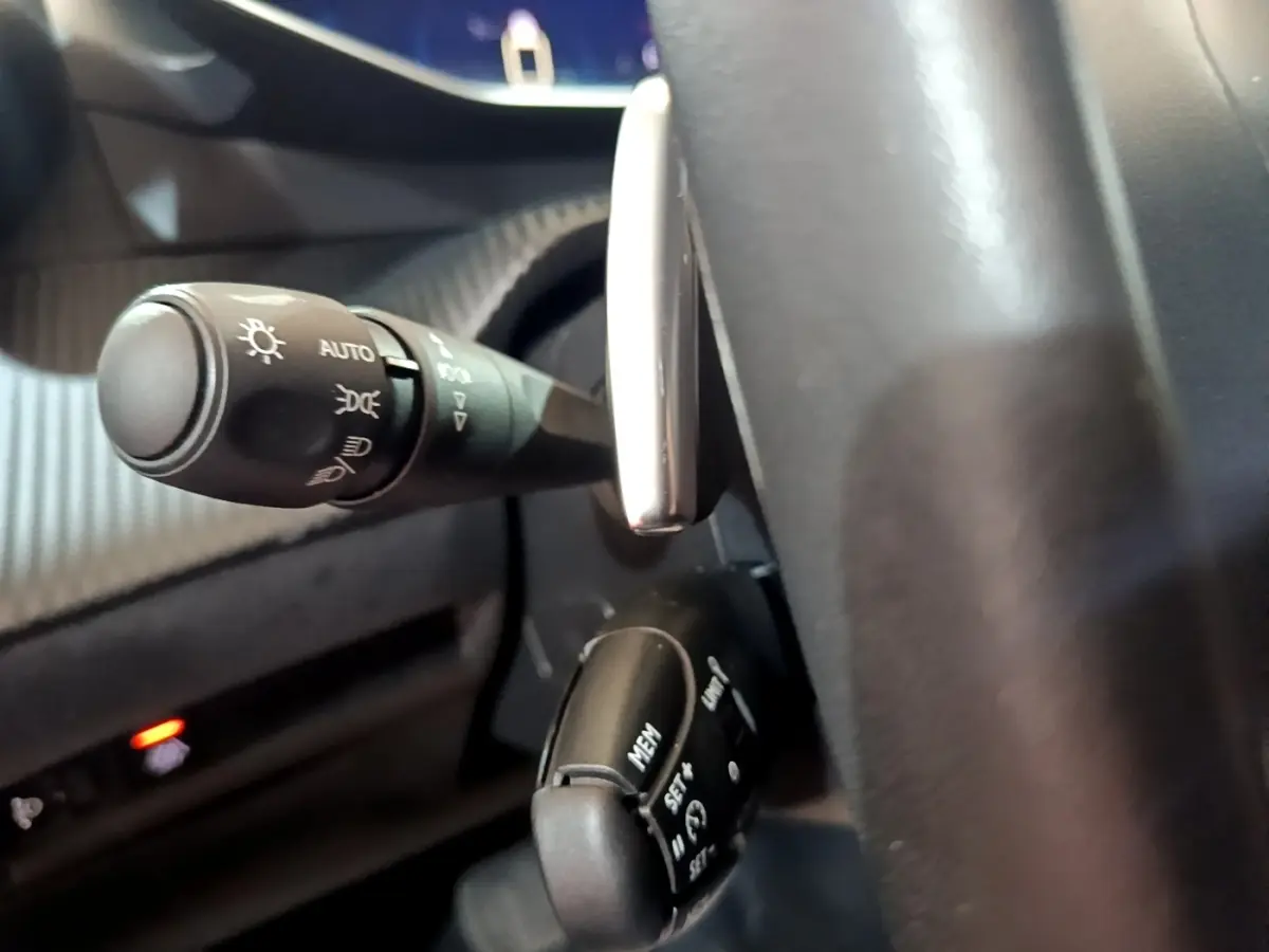 Gros plan sur le commodo des phares et le régulateur de vitesse derrière le volant cuir d’un Peugeot 2008 noir.
