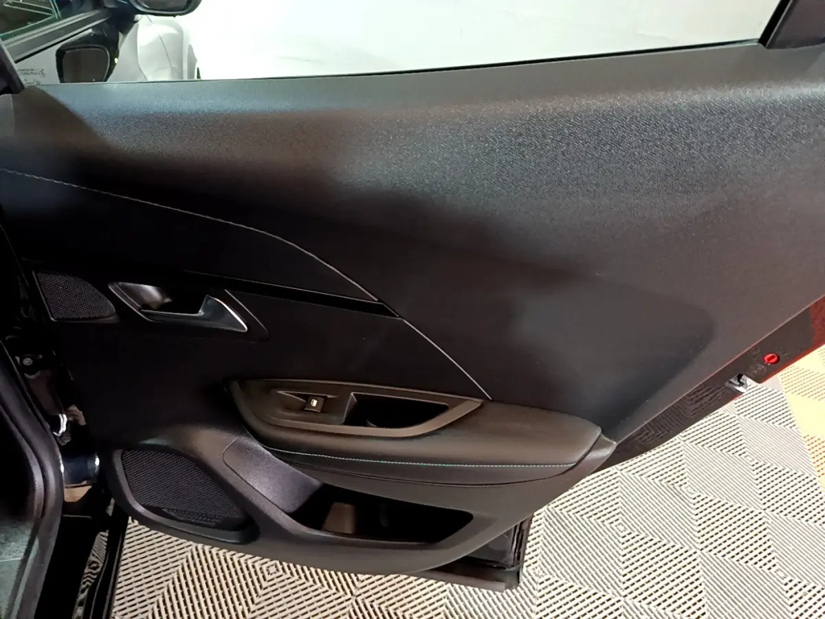 Vue rapprochée de la porte intérieure côté gauche noire du Peugeot 2008 2021 avec commande de vitre et haut-parleur intégré.