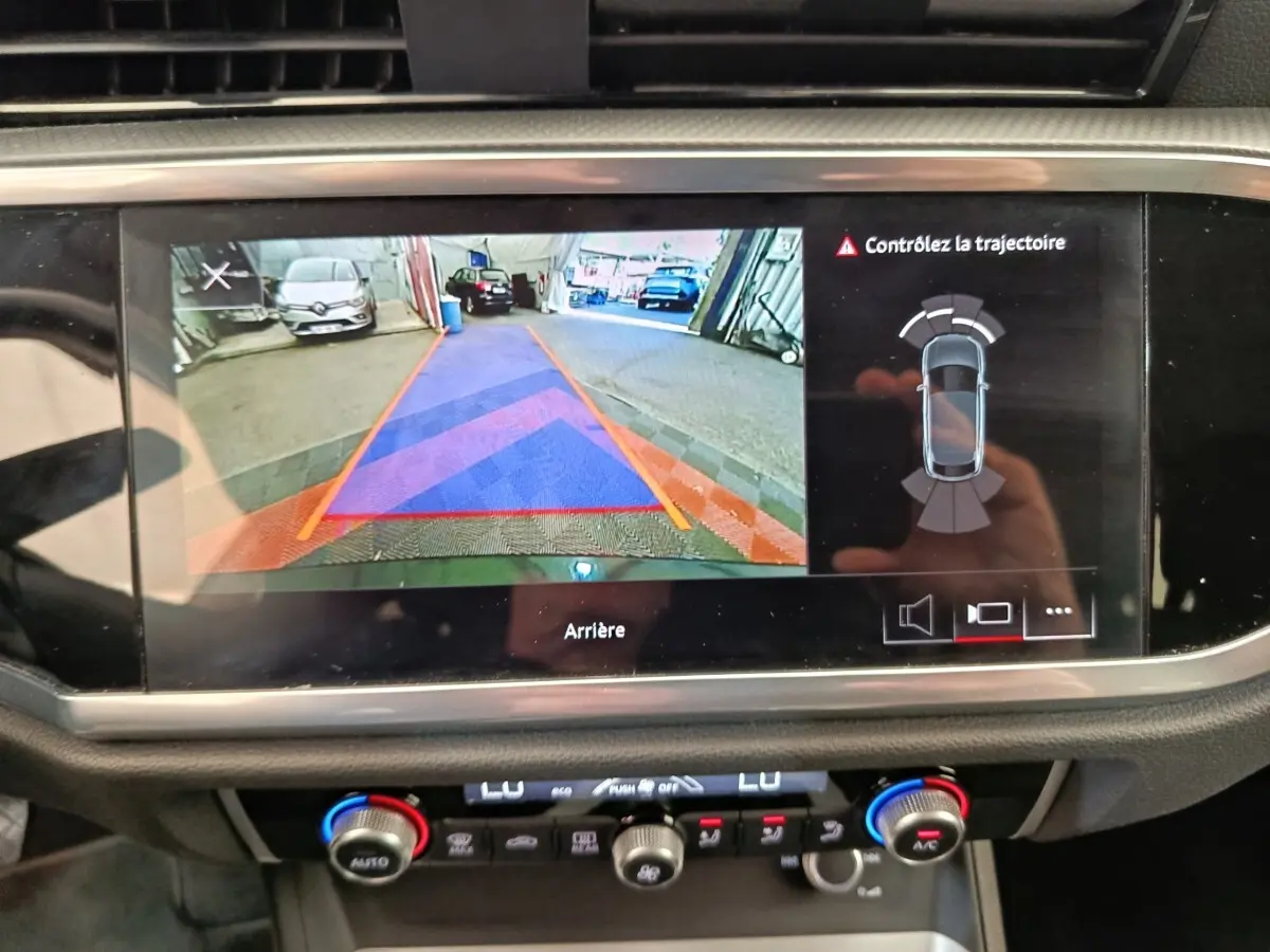 Écran tactile central montrant la caméra de recul et l'aide au stationnement du tableau de bord d'Audi Q3 Sportback noir.