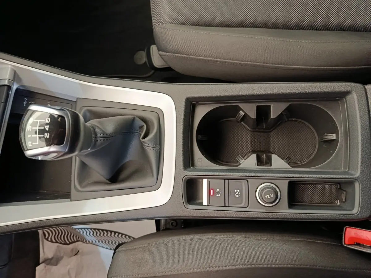 Gros plan sur la console centrale avec levier de vitesses manuel et porte-gobelets dans l'Audi Q3 Sportback noir.