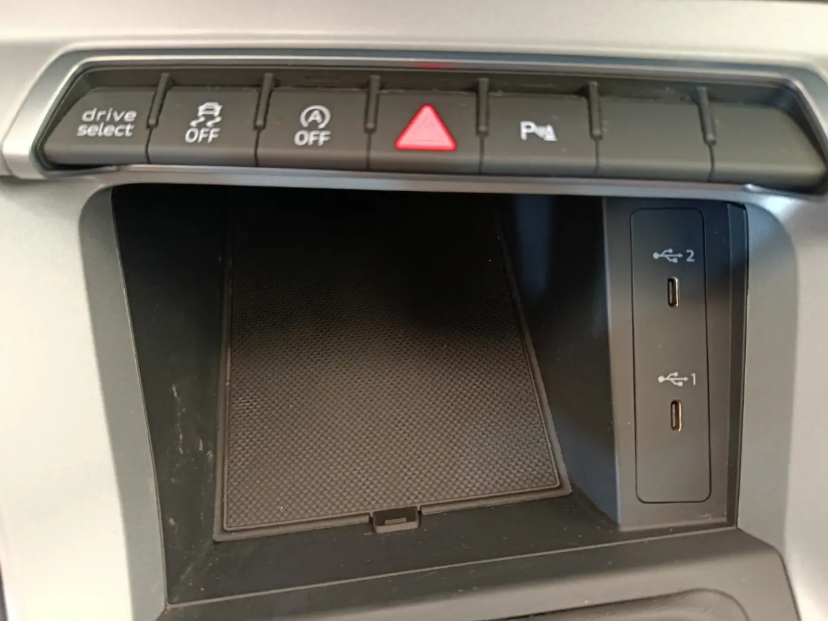 Vue rapprochée de la console centrale noire de l'Audi Q3 Sportback 35 TDI avec boutons de contrôle et ports USB.