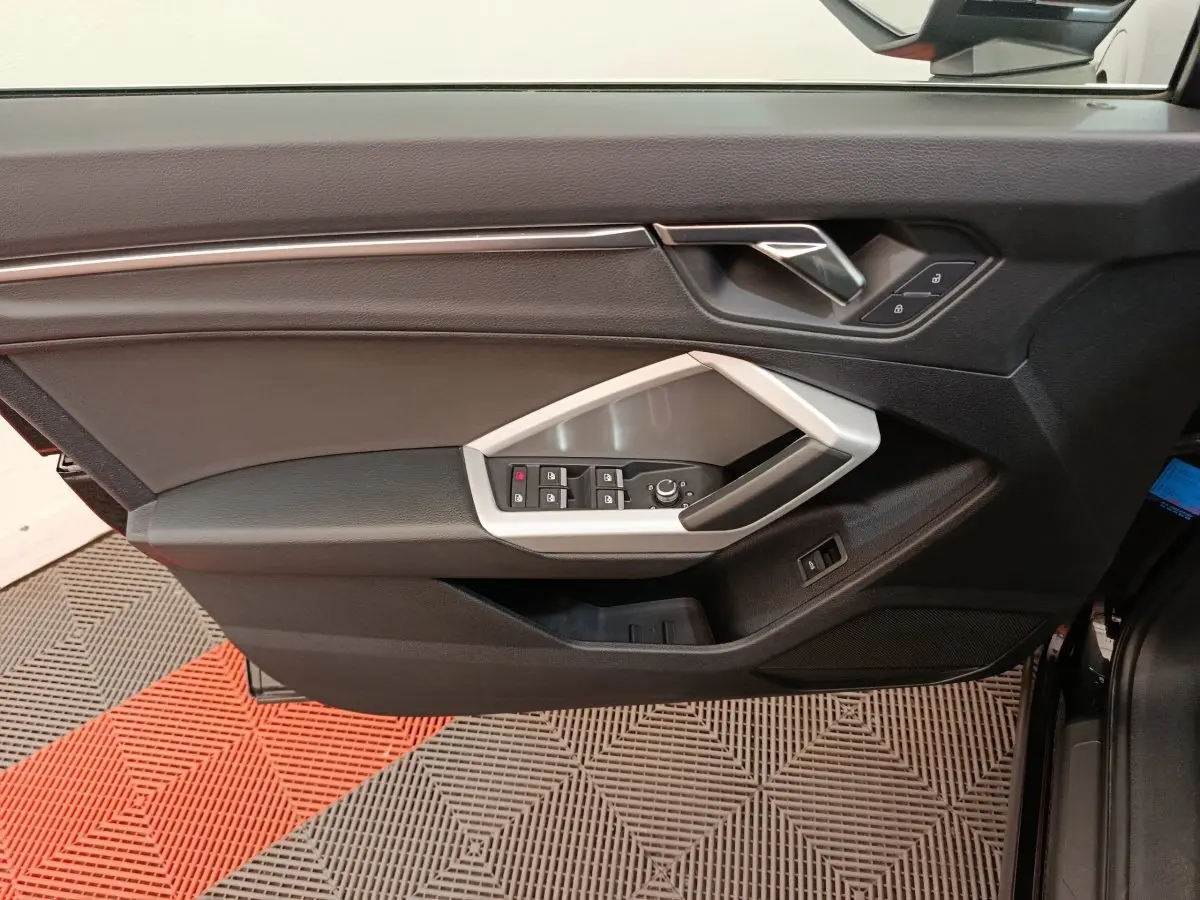 Porte avant gauche noire d’Audi Q3 Sportback 2023 avec commandes électriques et poignée argentée.