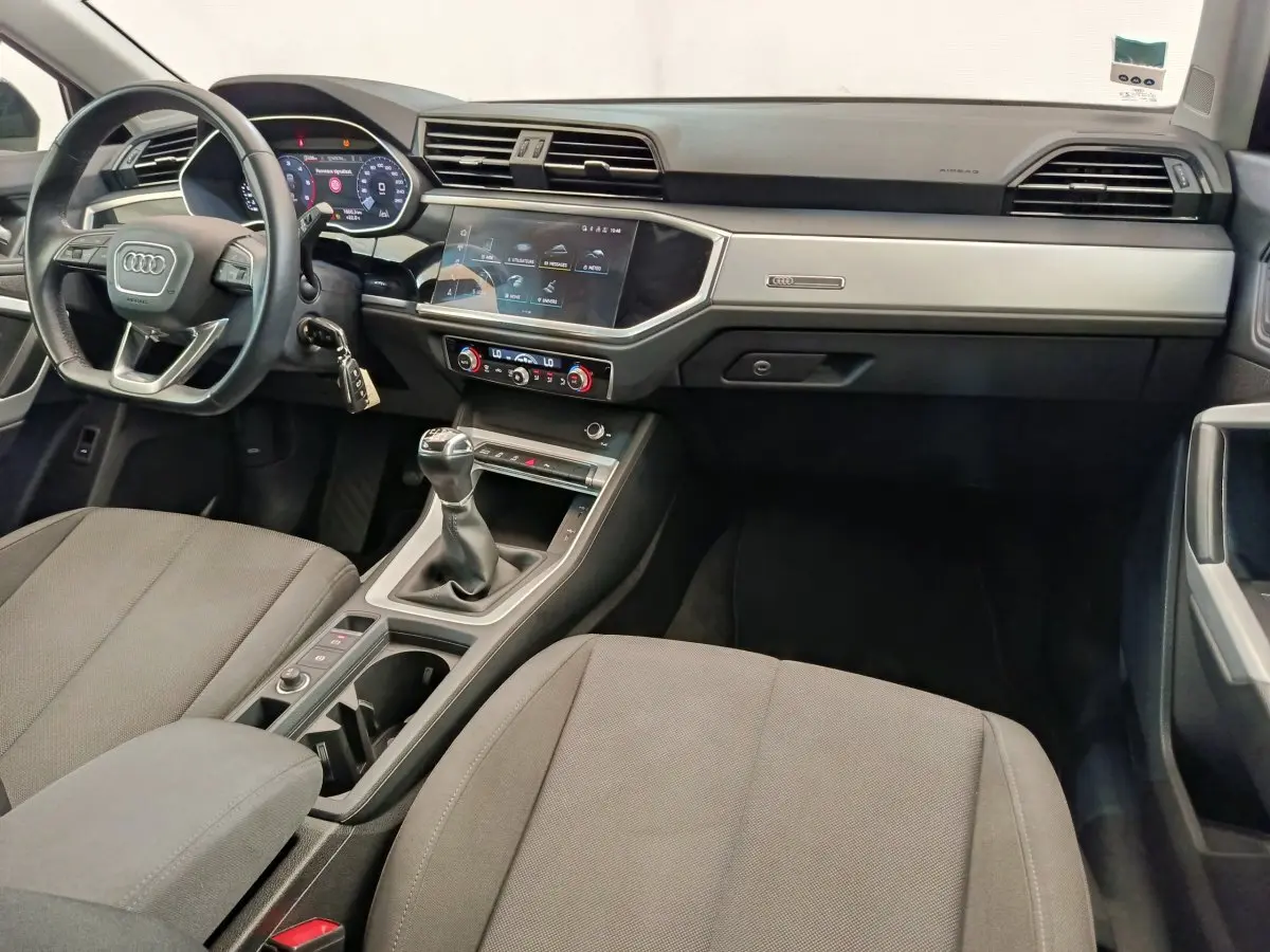 Intérieur avant de l'Audi Q3 Sportback noir 2023, vue du tableau de bord avec volant cuir et boîte manuelle.