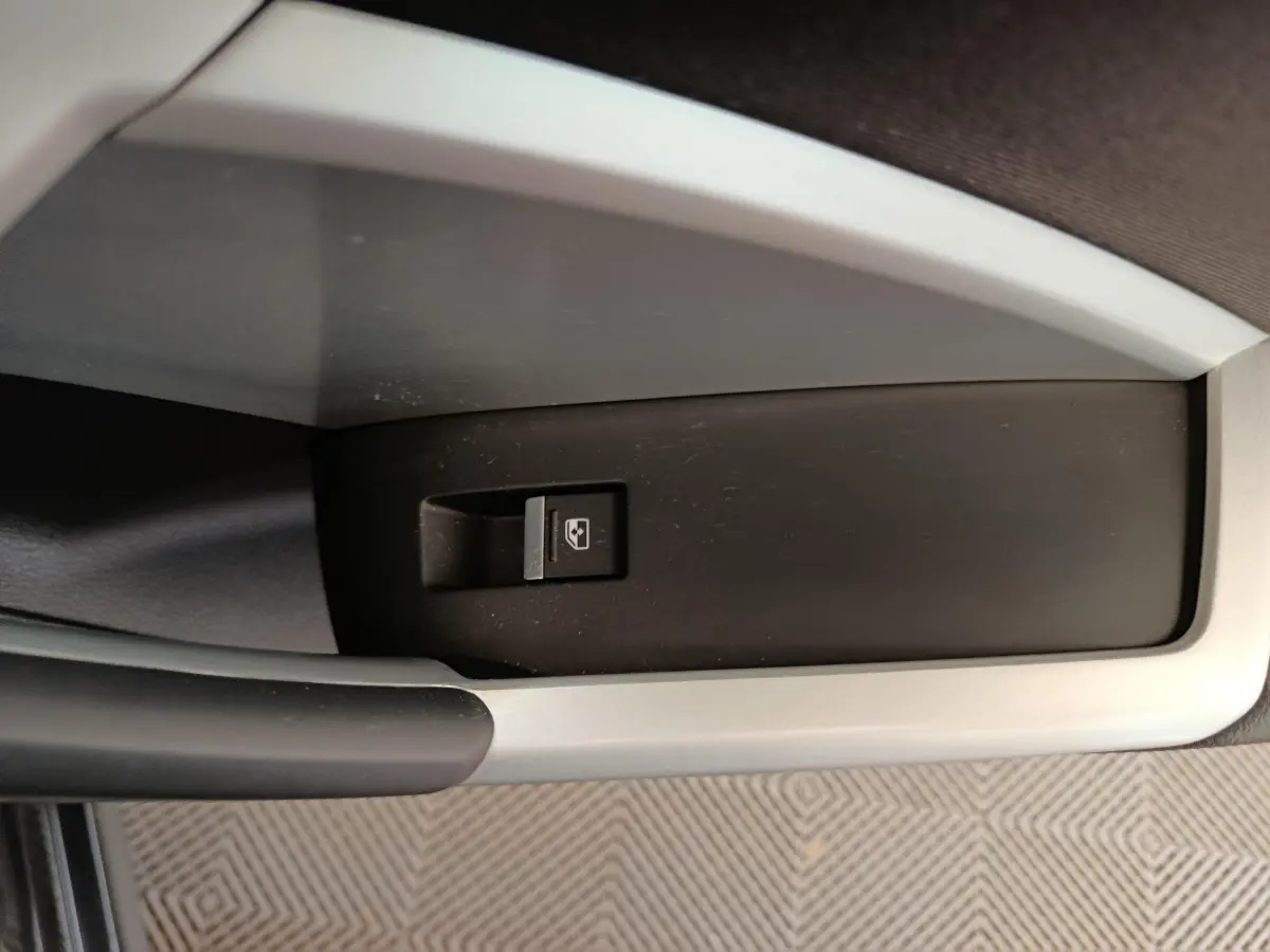 Gros plan sur le bouton de commande de lève-vitre dans l'accoudoir côté conducteur de l'Audi Q3 Sportback noir 2023.