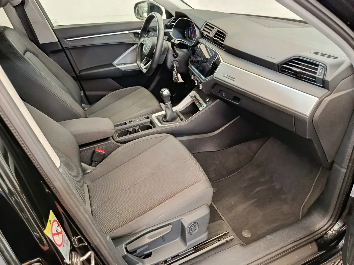 Vue intérieure côté conducteur de l'Audi Q3 Sportback 35 TDI 150 Business Line 2023 avec volant cuir et tableau de bord moderne.