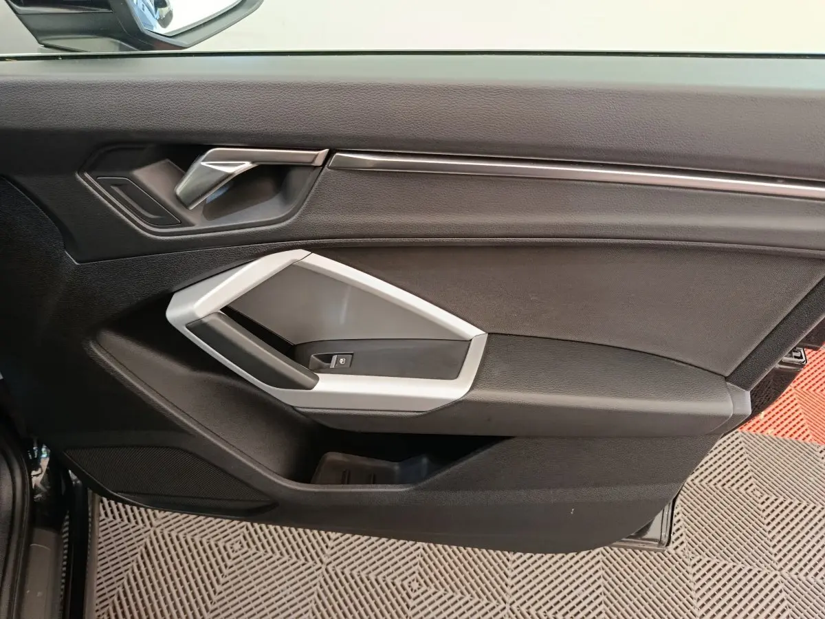 Vue intérieure de la porte avant gauche noire de l'Audi Q3 Sportback 35 TDI Business Line avec poignée argentée.