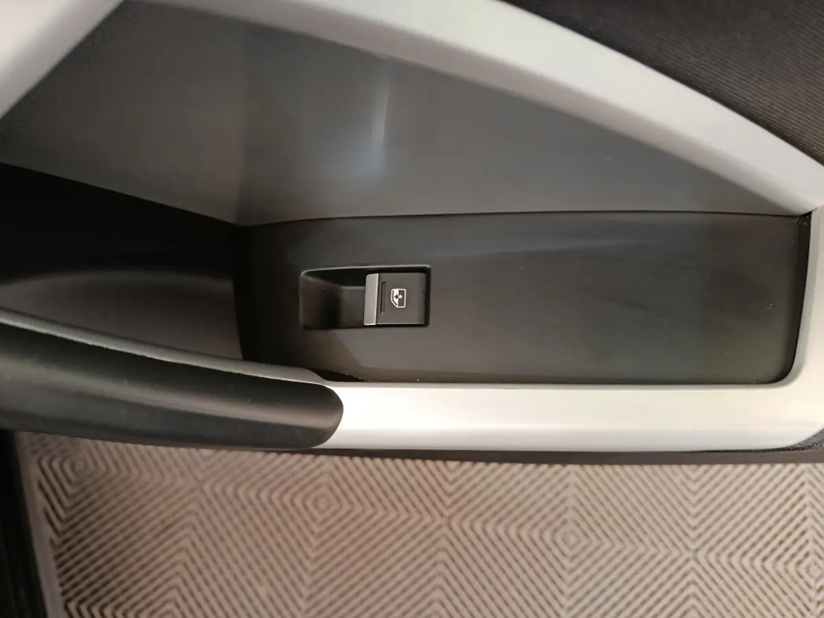 Bouton de commande de lève-vitre électrique sur la porte intérieure côté gauche d’un Audi Q3 Sportback noir.