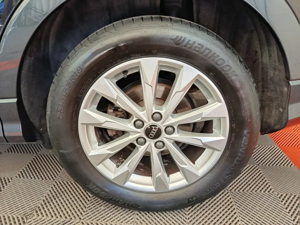 Gros plan sur la roue avant droite d’un Audi Q3 Sportback noir, jante alliage argentée à 10 branches.