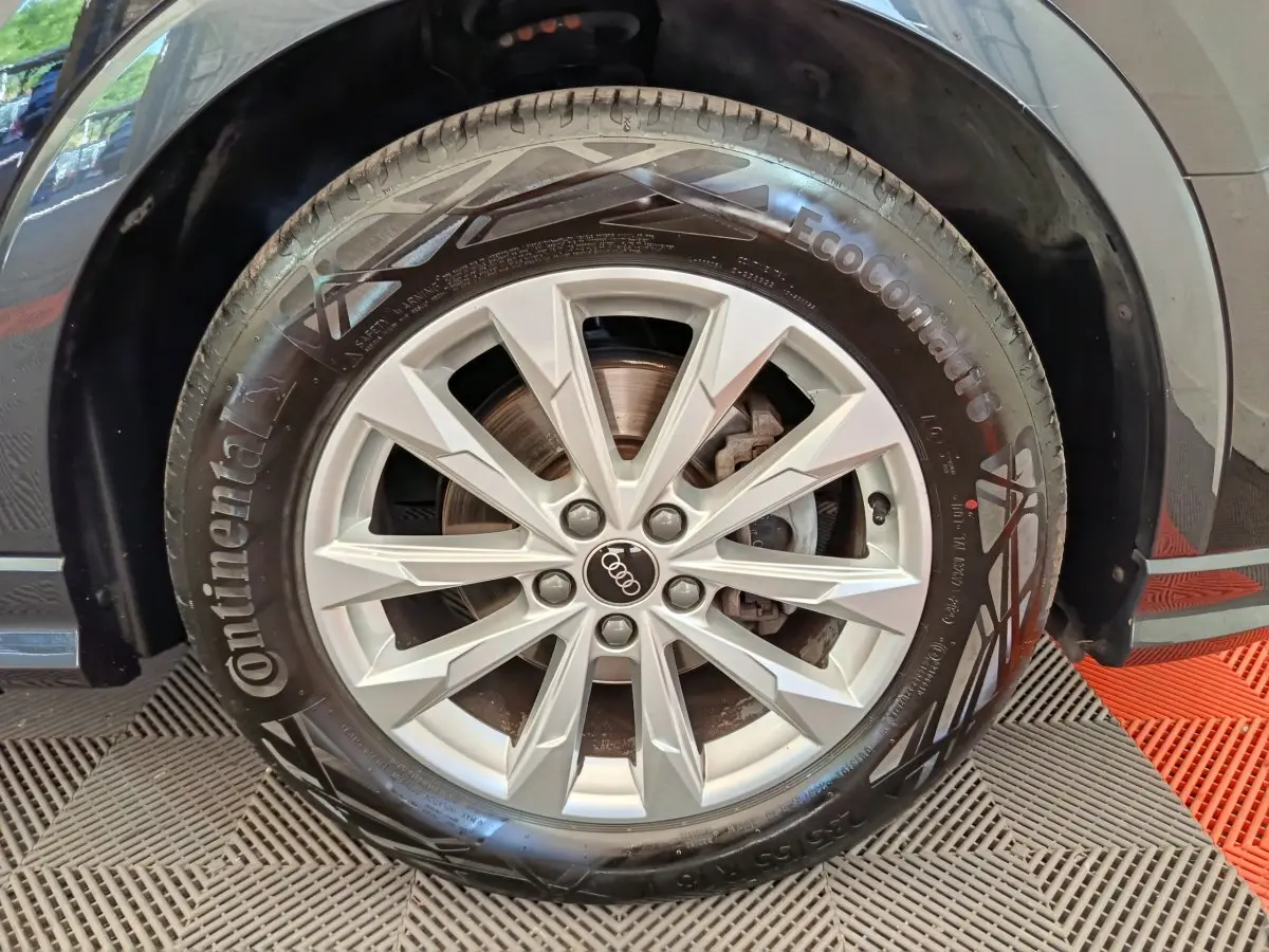 Gros plan sur la roue avant droite d’un Audi Q3 Sportback noir, jante alliage argentée et pneu Continental.
