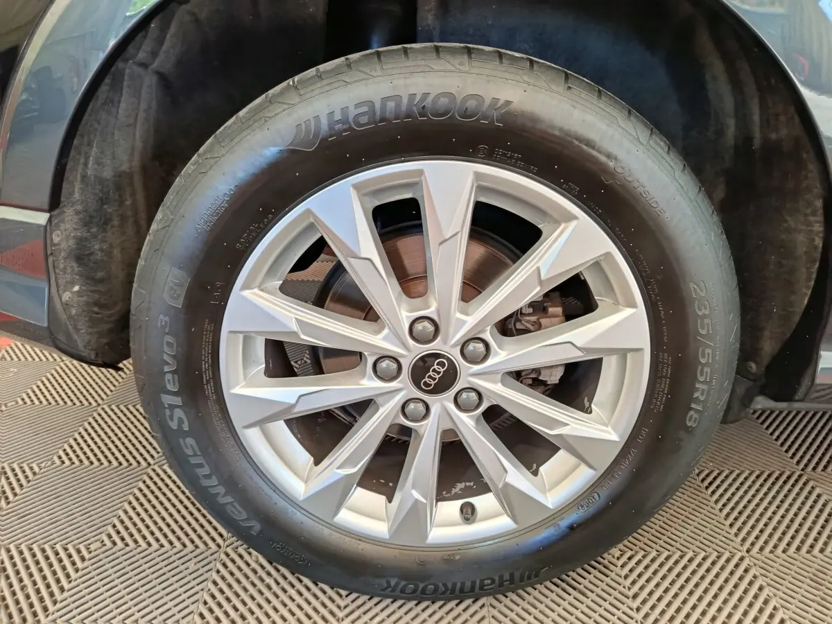 Gros plan sur la roue avant droite d’un Audi Q3 Sportback noir, avec jante alliage argent et pneu Hankook.