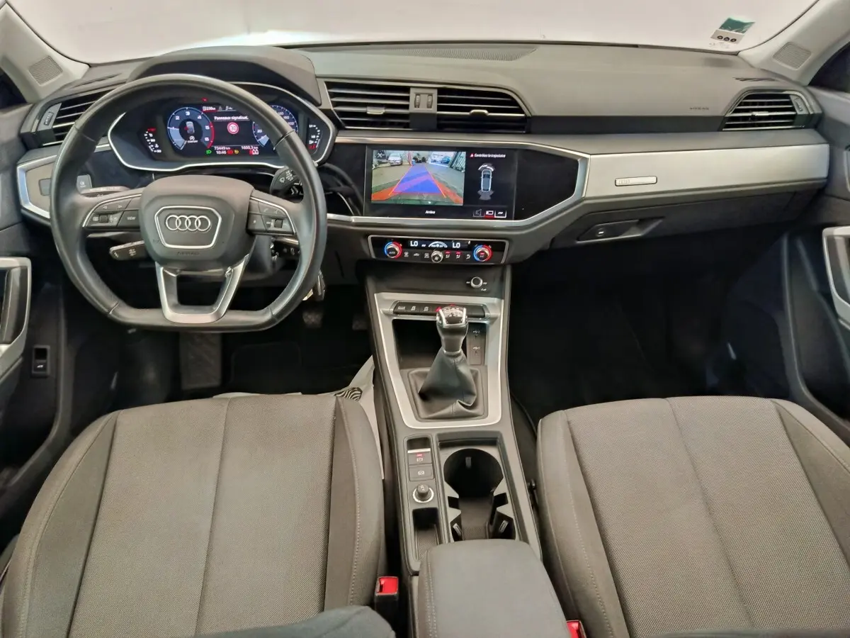 Vue intérieure avant de l’Audi Q3 Sportback 35 TDI Business Line 2023, volant cuir, écran tactile et levier de vitesse manuel.