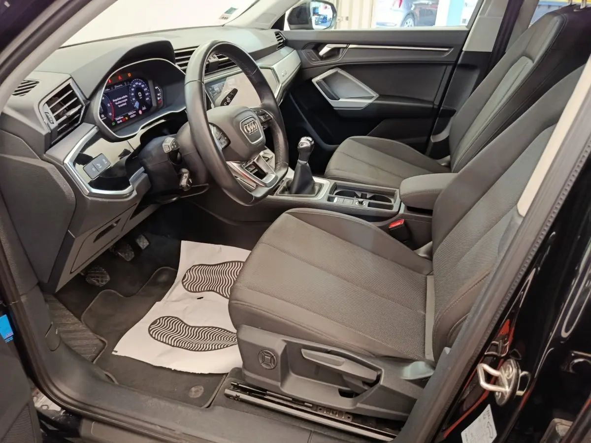 Intérieur avant droit de l’Audi Q3 Sportback noir 2023, volant cuir multifonctions et boîte manuelle visible.