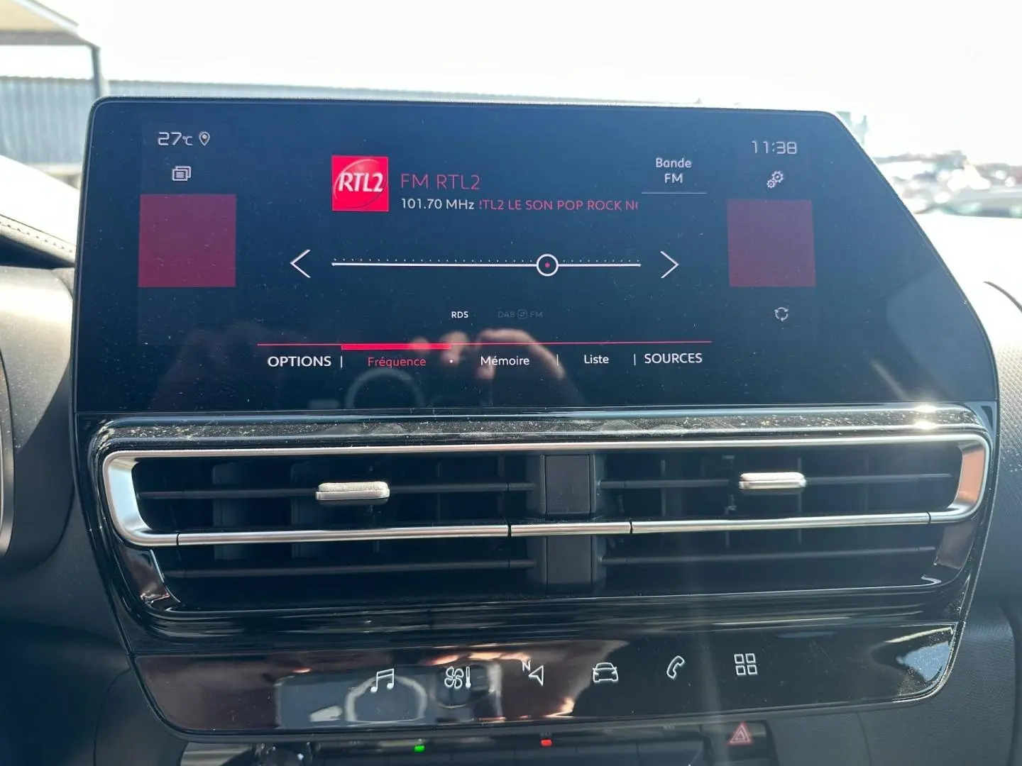 Écran tactile central allumé avec radio FM RTL2, entouré de sorties d'air et commandes tactiles noires brillantes.