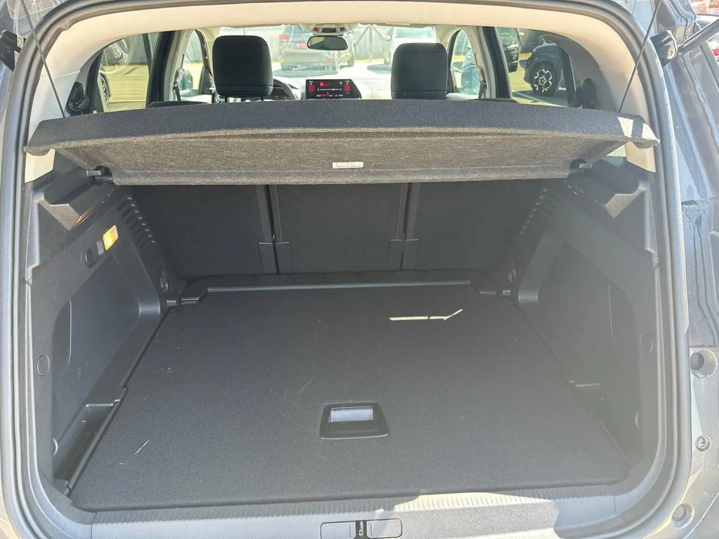 Coffre ouvert vu de l’arrière d’un Citroën C5 Aircross gris Platinium avec cache-bagages et sièges arrière visibles.