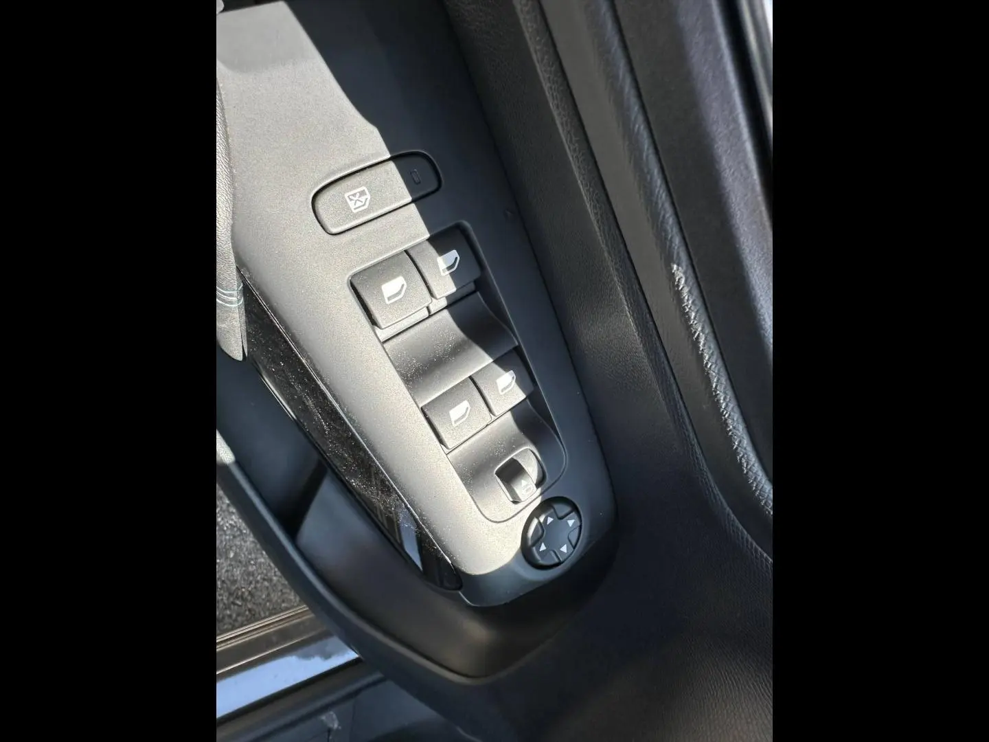 Gros plan sur les commandes des vitres électriques côté conducteur du Citroën C5 Aircross gris Platinium, intérieur noir.