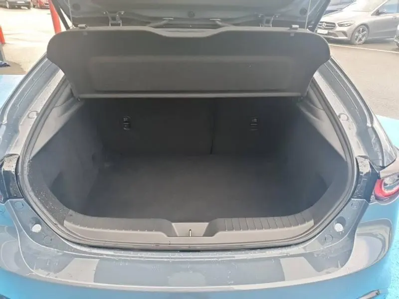 Coffre ouvert vu de l'arrière d'une Mazda3 2025 Platinum Quartz Métallisé, intérieur noir spacieux et propre.