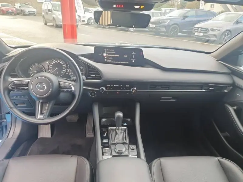 Intérieur noir de la Mazda3 2025, vue frontale du tableau de bord avec écran multifonction et volant cuir multifonction.