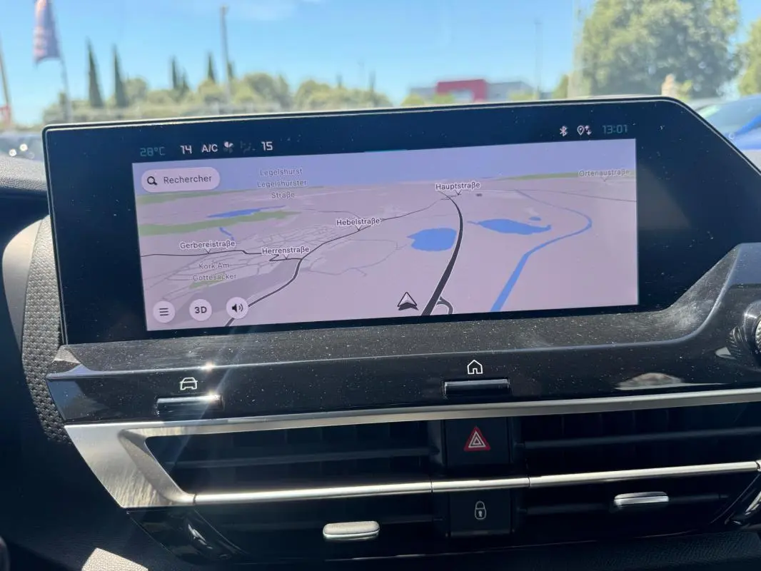 Écran tactile central du tableau de bord de la Citroën C4 hybride blanche, affichant la navigation GPS en plein jour.