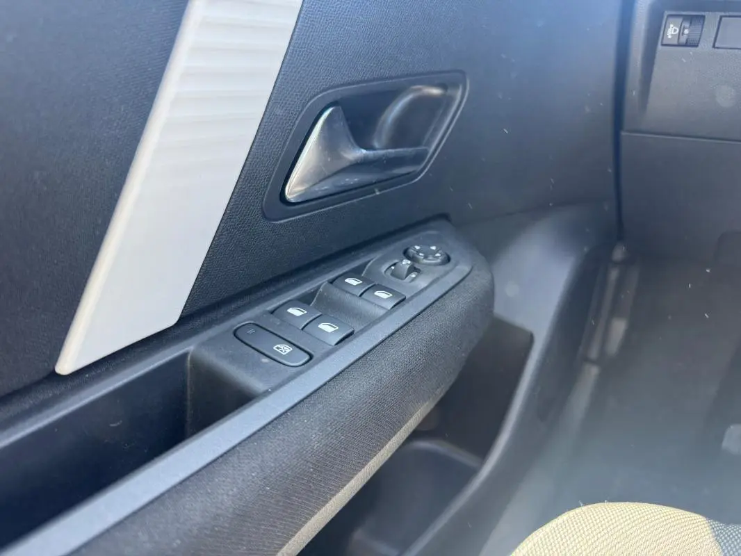 Gros plan sur la commande des vitres électriques côté conducteur d’une Citroën C4 blanche hybride 2025.