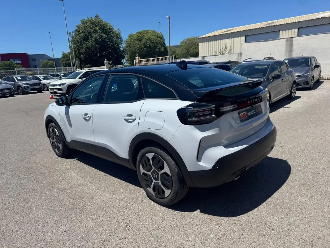 Vue 3/4 arrière droite d'une Citroën C4 hybride blanche avec toit noir et jantes alliage 18 pouces.