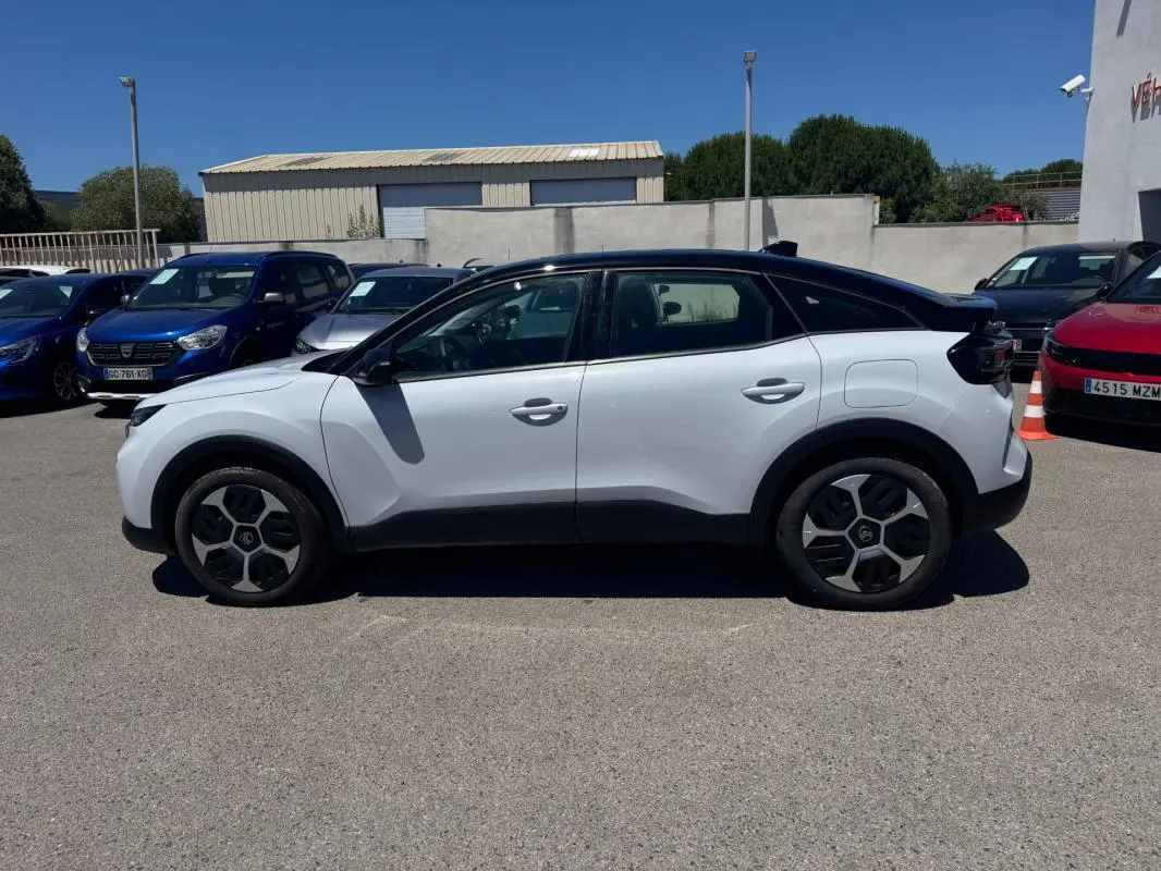 Vue de profil côté gauche d'une Citroën C4 hybride blanche avec toit noir et jantes alliage 18 pouces.