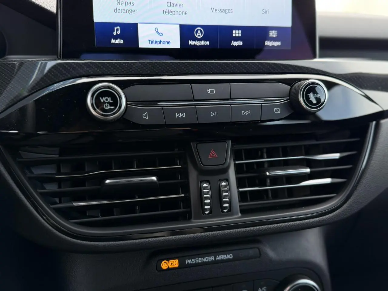 Gros plan sur la console centrale du Ford Kuga 2023, avec commandes audio et écran tactile visible.