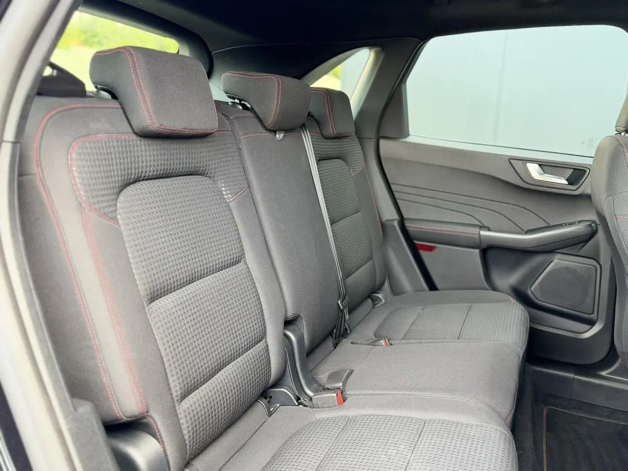 Vue intérieure côté droit des sièges arrière noirs avec surpiqûres rouges du Ford Kuga 2023 finition ST-Line.