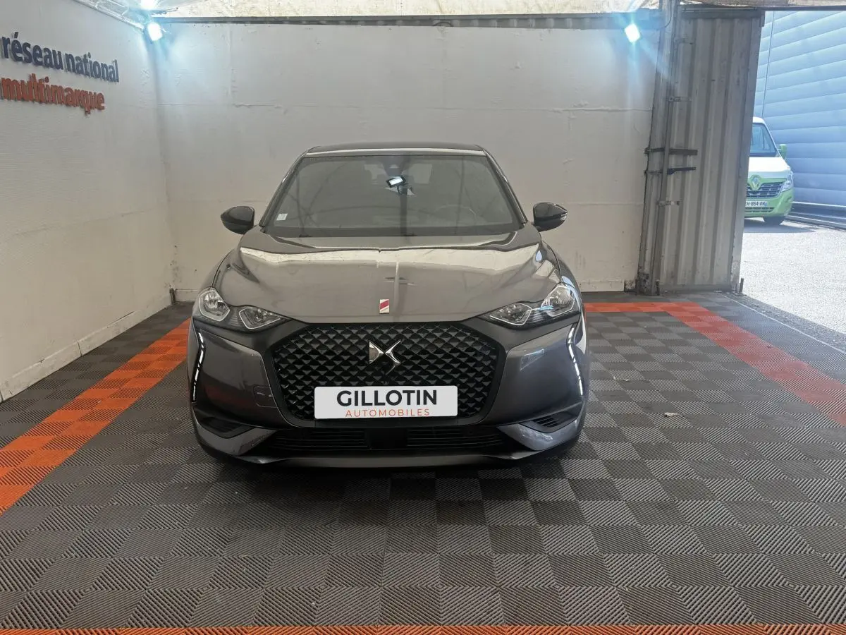 Vue frontale d'un DS3 Crossback gris foncé avec calandre hexagonale et logo DS bien visible.