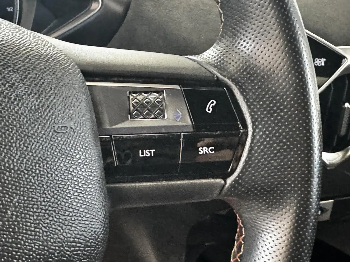 Gros plan sur le volant en cuir perforé du DS3 Crossback gris foncé, avec commandes multifonctions visibles.
