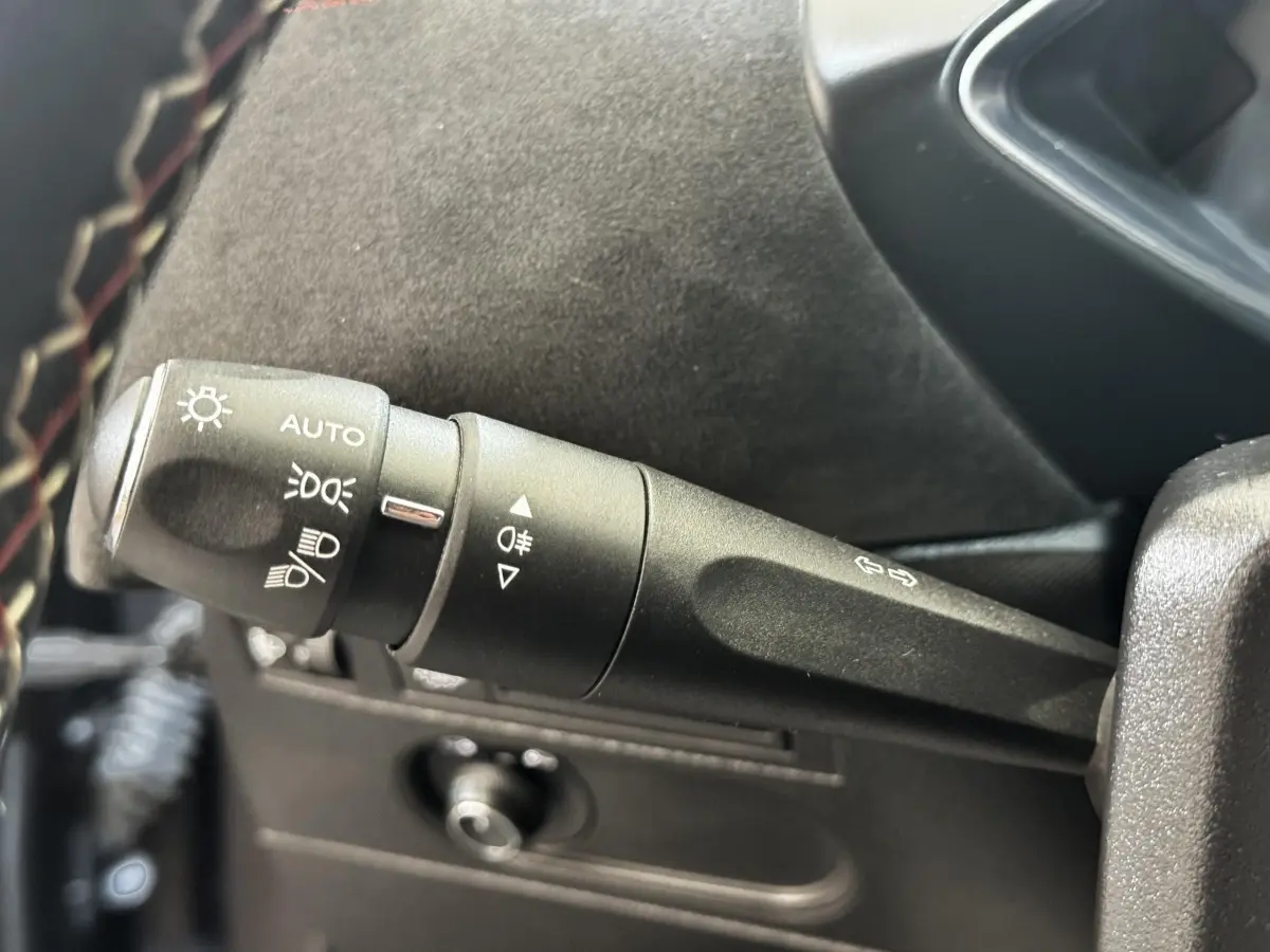 Gros plan sur la commande des feux et clignotants à gauche du volant cuir dans un DS3 Crossback gris foncé 2021.