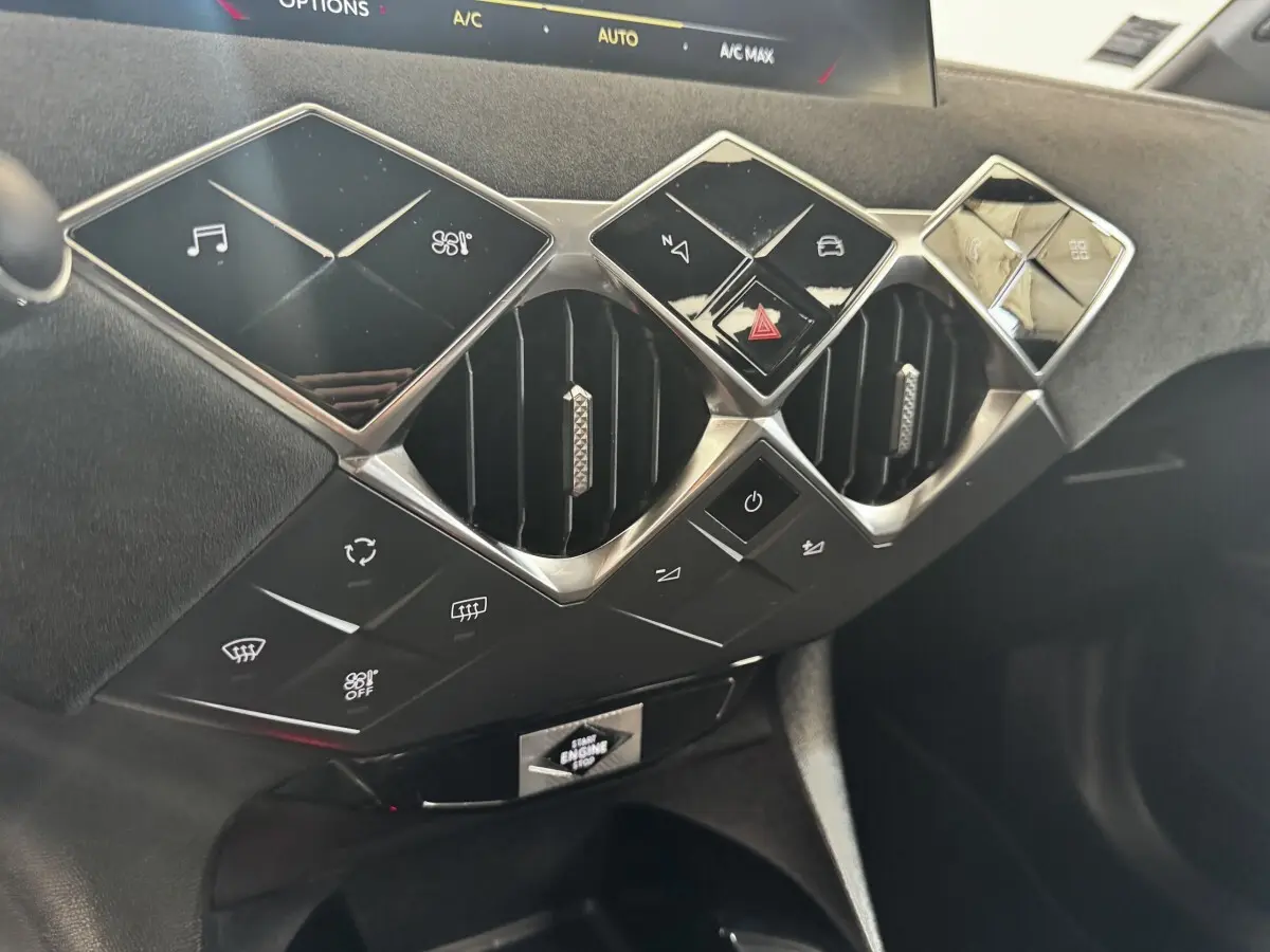 Gros plan sur la console centrale du DS3 Crossback gris foncé, mettant en valeur les boutons carrés et les aérateurs hexagonaux chromés.