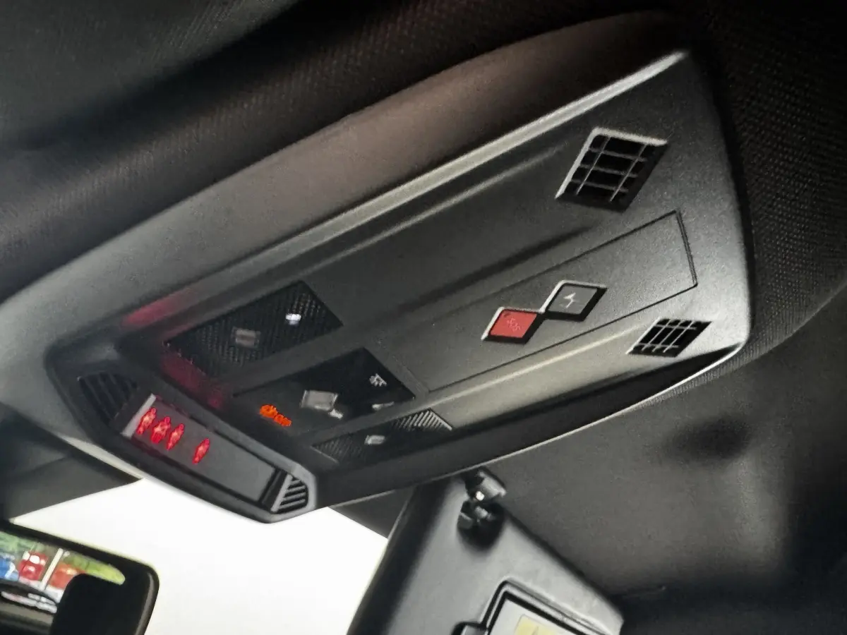 Vue en contre-plongée du plafonnier noir avec commandes et voyants rouges du DS3 Crossback gris foncé 2021.