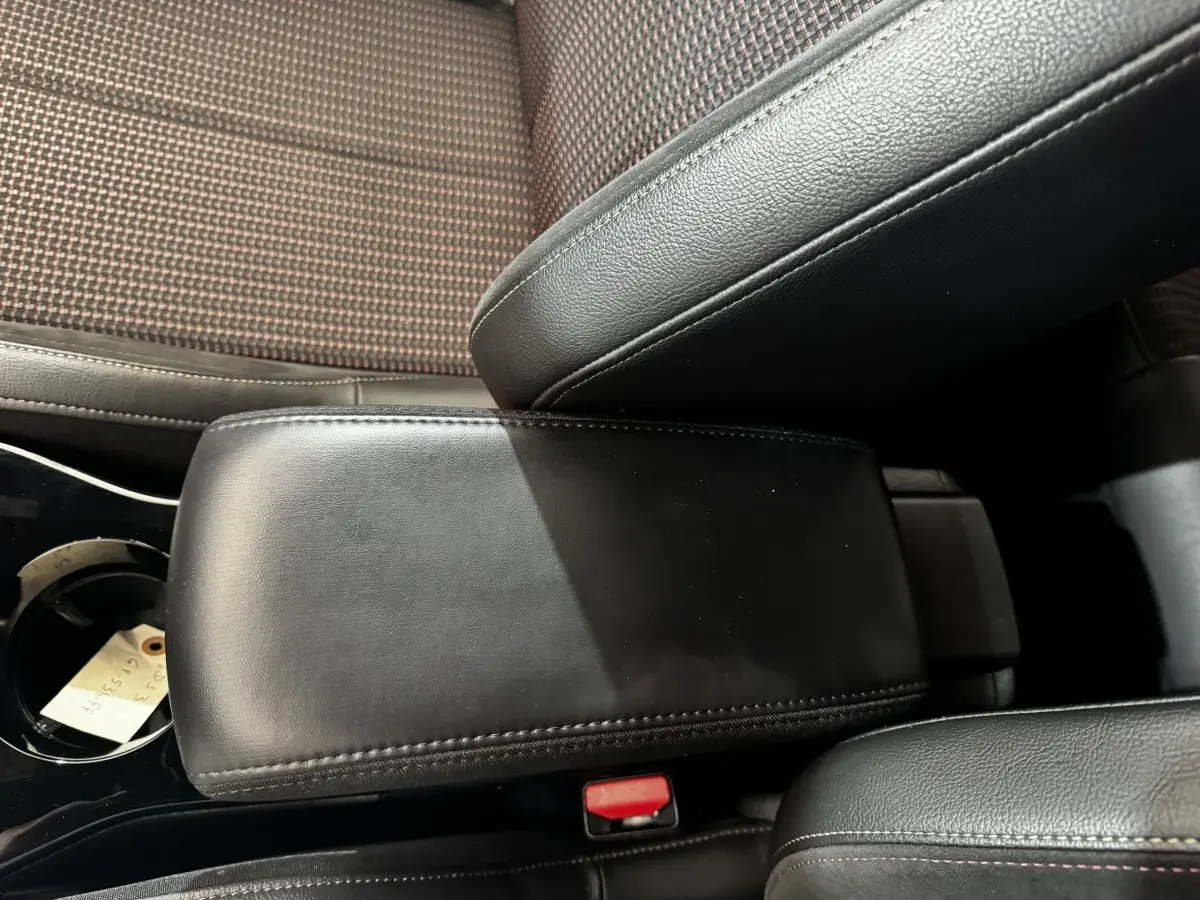 Gros plan sur l'accoudoir central en cuir noir et la console entre les sièges avant du DS3 Crossback gris foncé.