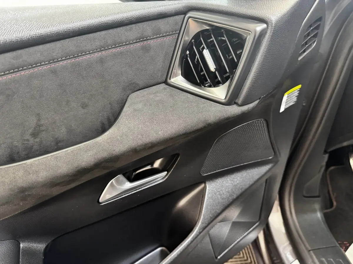 Gros plan sur la porte avant gauche intérieure du DS3 Crossback gris foncé, avec garniture en alcantara et sortie d'air carrée.