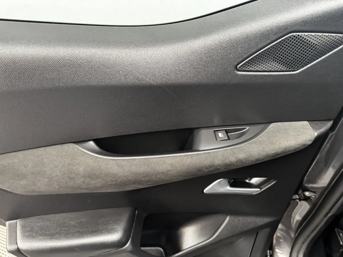 Gros plan sur la porte côté gauche du DS3 Crossback gris foncé, montrant la poignée, le bouton de verrouillage et un insert en tissu gris.