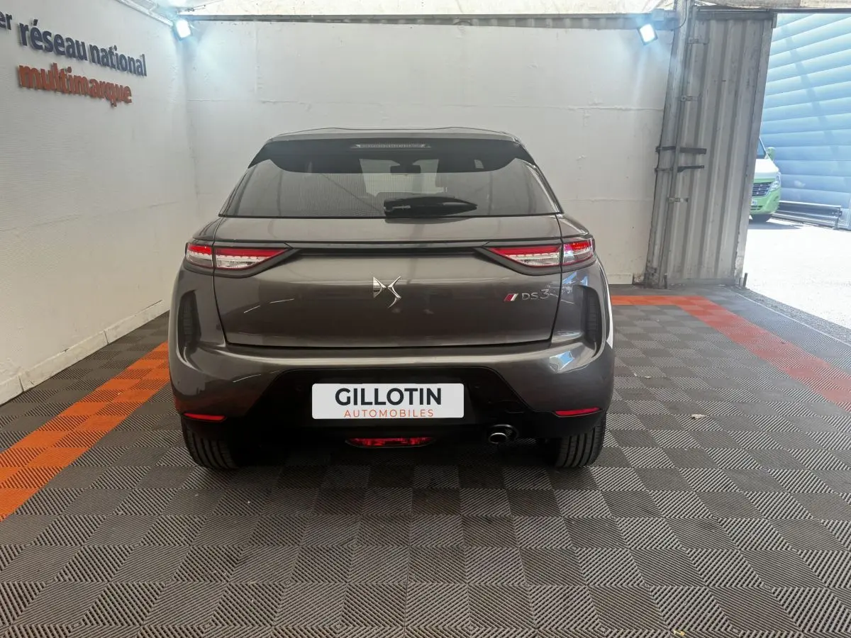Vue arrière d'un DS3 Crossback gris foncé avec feux LED étirés et logo DS centré, en intérieur showroom.