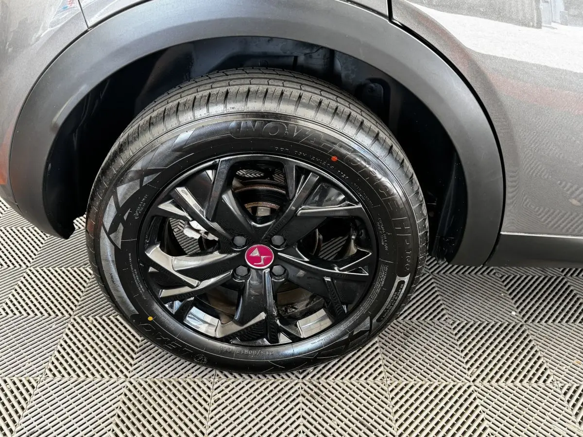 Gros plan sur la roue arrière droite du DS3 Crossback gris foncé, mettant en valeur la jante noire au logo DS rouge.