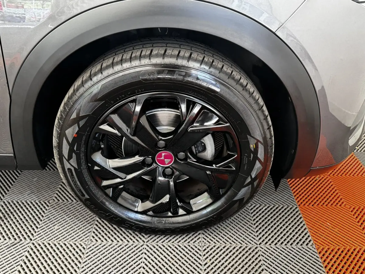 Gros plan sur la roue avant droite du DS3 Crossback gris foncé avec jante noire brillante et logo DS rouge.