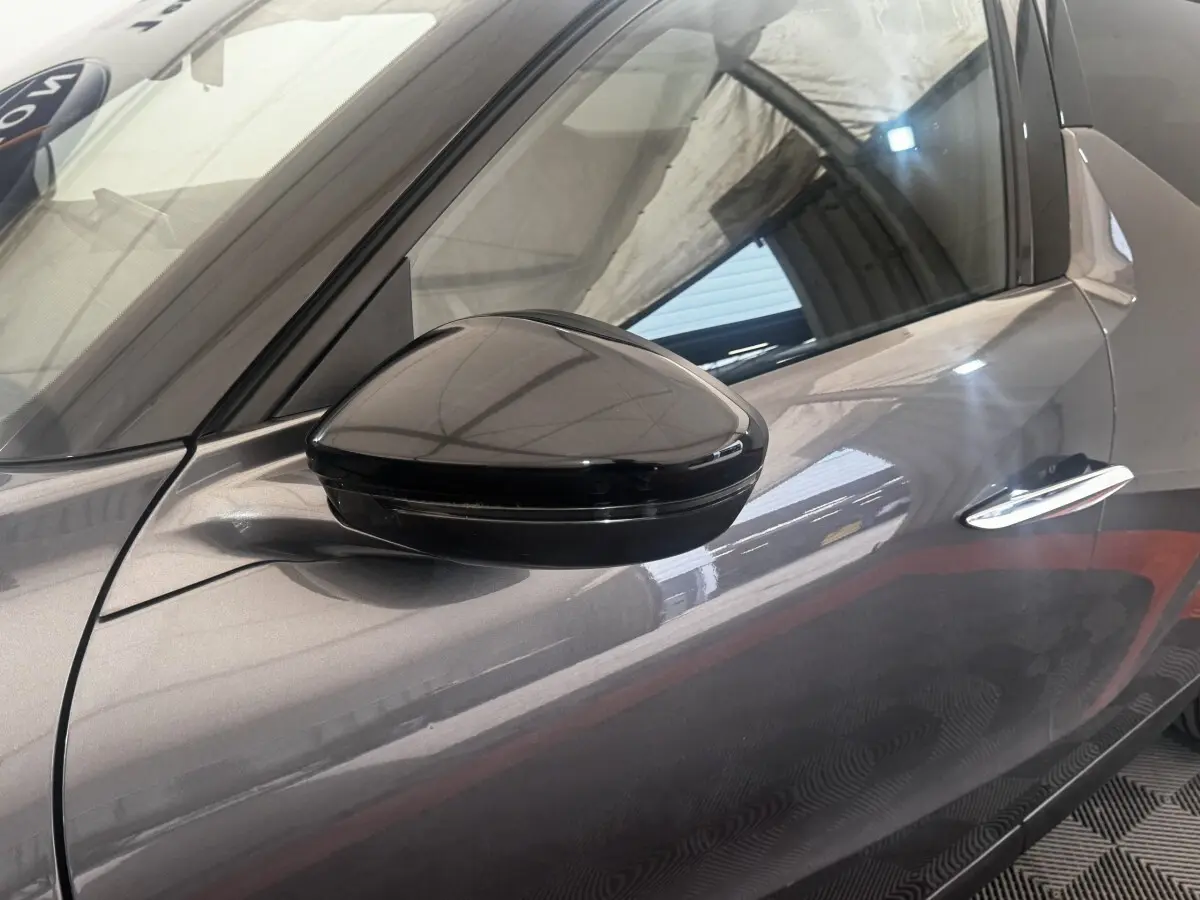 Gros plan sur le rétroviseur côté gauche d’un DS3 Crossback gris foncé, avec reflet de l’environnement intérieur.