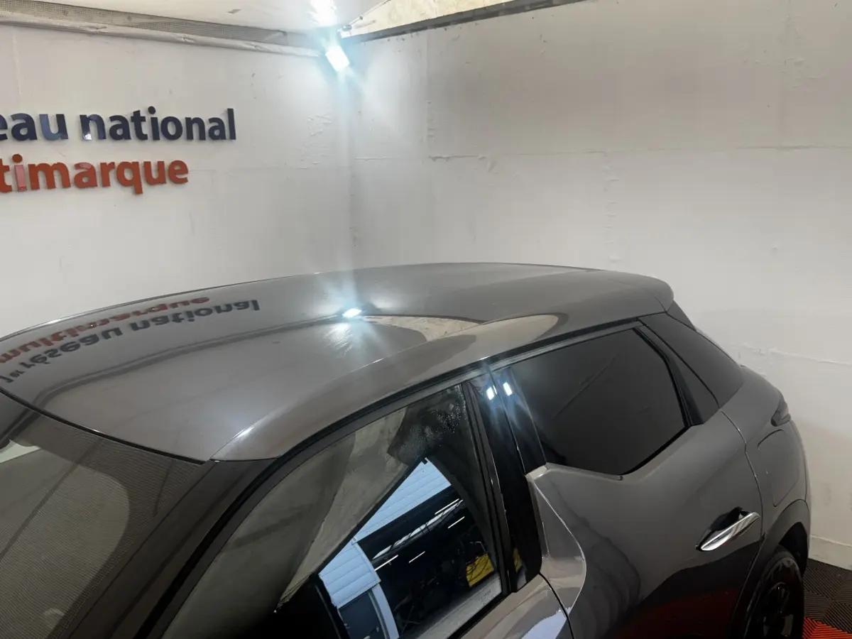 Vue 3/4 arrière droite du DS3 Crossback gris foncé avec vitres teintées et poignées de porte chromées.