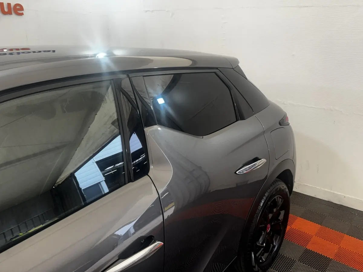 Vue côté droit arrière du DS3 Crossback gris foncé, mettant en valeur la poignée de porte chromée et les jantes noires.