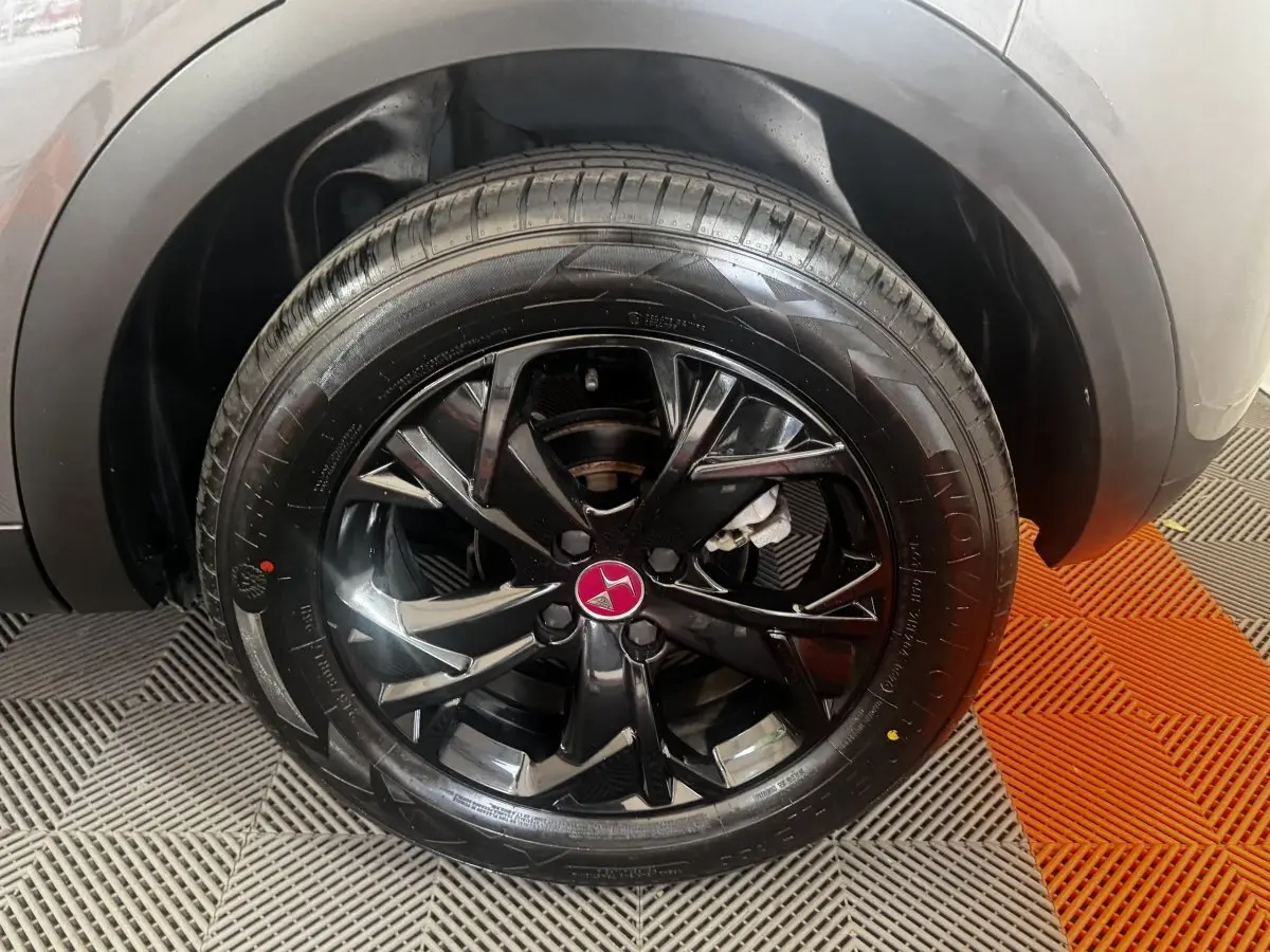 Gros plan sur la roue avant droite du DS3 Crossback gris foncé avec jante noire brillante et logo DS rouge au centre.