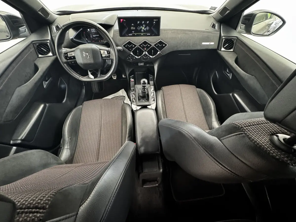 Vue intérieure avant du DS3 Crossback gris foncé, volant cuir multifonctions, écran tactile central et sièges tissu cuir bicolores.